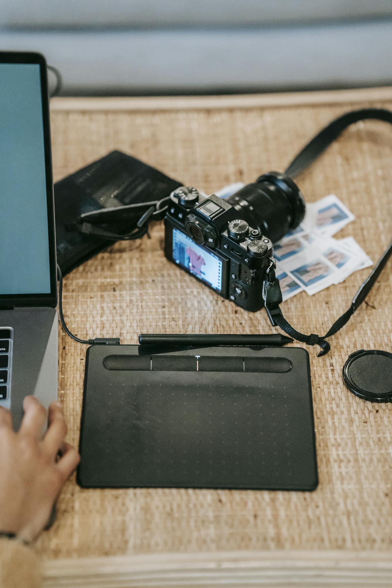 High angle of crop anonymous designer with netbook near graphics tablet and professional photo camera on desk